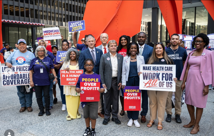 Elected officials and advocates rally in Chicago holding campaign signs