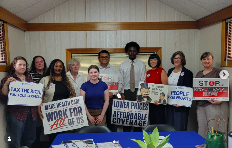 Advocates hold campaign signs at a town hall meeting